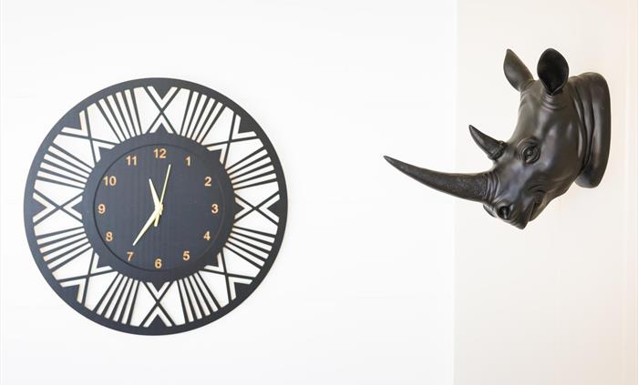 African styled black and gold clock and wall-mounted black rhino head.
